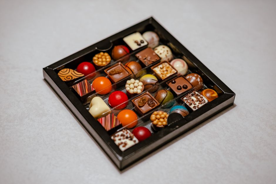 An open box of assorted pralines on a dark surface