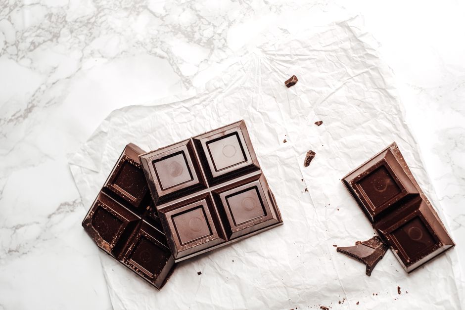 A dark chocolate bar resting on a marble surface